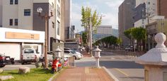 a city street with cars parked on both sides and tall buildings in the back ground