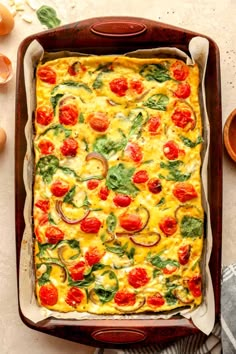 a casserole dish with tomatoes, spinach and cheese in it on a table