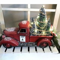 an old red truck with a christmas tree on the back is sitting in front of a window