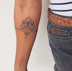 a woman with a tattoo on her arm next to a man's leg wearing jeans