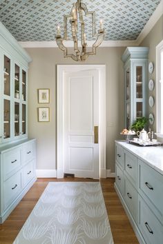 a kitchen with white cabinets and a chandelier hanging from the ceiling above it