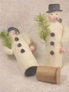 two snowmen are holding christmas trees in their hands and one is wearing a top hat