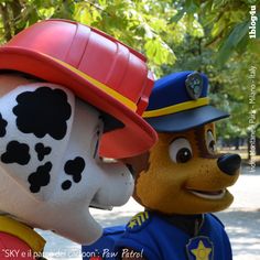 two mascot dogs dressed as firemen talking to each other in front of some trees