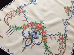 an embroidered table cloth with flowers on it