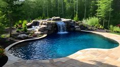 an outdoor pool with waterfall and stone patio