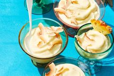 three glasses filled with dessert sitting on top of a blue table