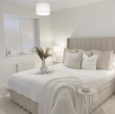 a bed with white linens and pillows in a bedroom next to two lamps on either side of the bed