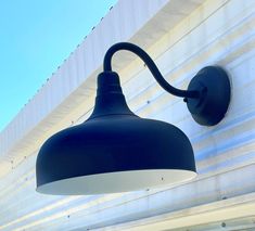 a blue light hanging from the side of a wall next to a white and gray building