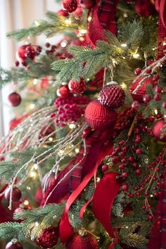 the christmas tree is decorated with red and green ornaments, pine cones, plaid ribbon and baubles