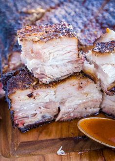 sliced pork chops on a wooden cutting board next to a bowl of dipping sauce