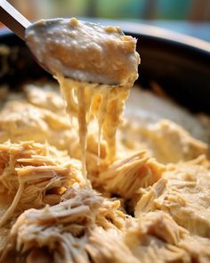 a spoon is lifting some food out of the casserole dish with meat and cheese