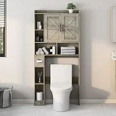 a white toilet sitting next to a wooden shelf filled with towels and other bathroom items