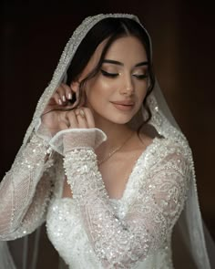 a woman in a wedding dress is wearing a veil and holding her hand to her ear