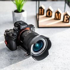 a camera sitting on top of a table next to a potted plant and wooden letters