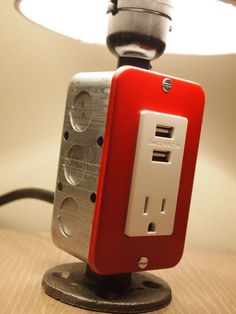 a red and white light switch sitting on top of a table next to a lamp