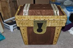 a brown and gold chest sitting on top of a floor next to a pile of clothes