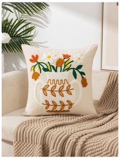 a white pillow sitting on top of a couch next to a plant and potted plant