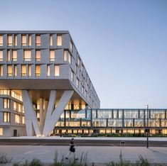 the building has many windows and is lit up at night, with people walking by