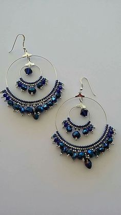 a pair of blue beaded hoop earrings on a white surface with silver earwires