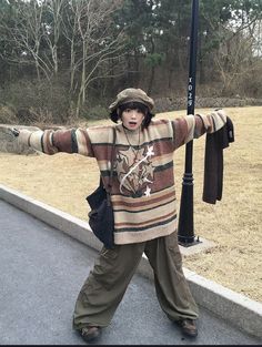 a person standing on the street with their arms out in front of a sign post