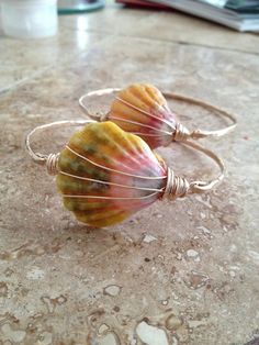 two seashells sitting on top of a table next to wire wrapped hoop earrings