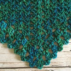 a crocheted green and blue doily sitting on top of a wooden table