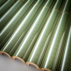 a close up view of green bamboo roofing tiles on a white surface with wood trimmings