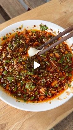 chopsticks in a bowl filled with food on top of a wooden table,