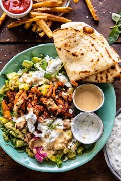 a salad and pita bread on a plate with dipping sauces next to it