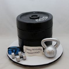 a birthday cake made to look like a kettle and some dumbbells on a plate