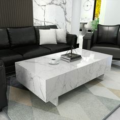 a living room filled with black leather couches and a white marble coffee table in the middle