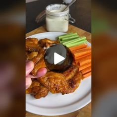 a plate with chicken wings, carrots and celery sticks on it next to a jar of ranch dressing