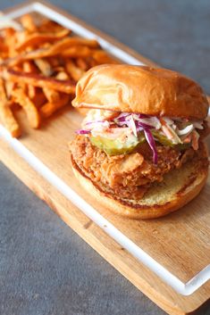 a fried chicken sandwich and french fries on a cutting board