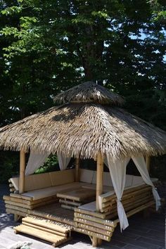 a wooden gazebo with a thatched roof