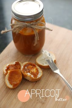 an open jar of jam next to some bread on a cutting board with a spoon