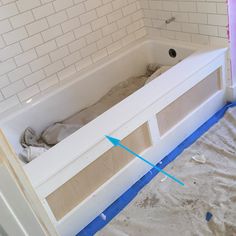 an unfinished bathtub in the middle of being remodeled with blue tape on the floor