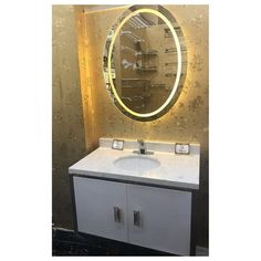 a bathroom sink with a lighted mirror above it