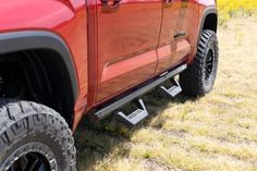 a red truck parked on top of a grass covered field