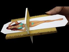 a person holding up a piece of paper cut out of the shape of a woman's body