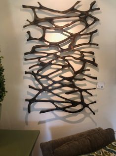 a wall sculpture made out of branches in the corner of a room with a couch