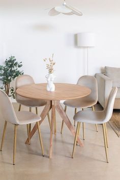 a dining room table with four chairs and a vase on the top, in front of a white wall