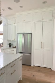 a kitchen with white cabinets and stainless steel refrigerator