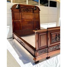 a bed with wooden headboard and foot board sitting on top of a white sheet