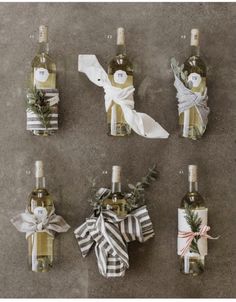 six wine bottles wrapped in ribbon and tied with twine bows, sitting next to each other