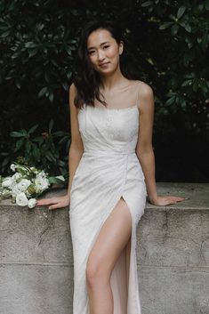 a woman in a white dress sitting on a ledge