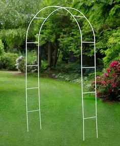 a white metal arch in the middle of a green lawn