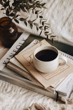 a cup of coffee sitting on top of a book next to a potted plant