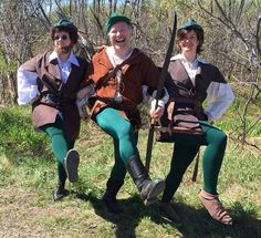 three people dressed up in costume posing for the camera with trees in the back ground