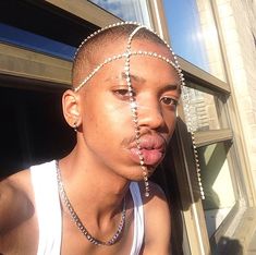 a young man sticking his tongue out with beads on his head