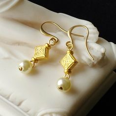 These dainty earrings consist of freshwater pearls suspended from flat diamond-shaped 24kt gold plated beads which are embossed on both sides with a quatrefoil pattern. They have 24kt gold plated ear wires. These earrings would be great for Roman re-enactments or for modern day wear. Limited edition design. 24kt gold plated ear wires. Length (from top of ear wire to bottom of earring) 4.2cm (1.65 inches) Please note: All photos are taken under natural light. However different computer screens, o Byzantine Earrings, Roman Costume, Quatrefoil Pattern, Ancient Jewelry, 24kt Gold, Dainty Earrings, Juno, Handmade Earrings, Ear Wires